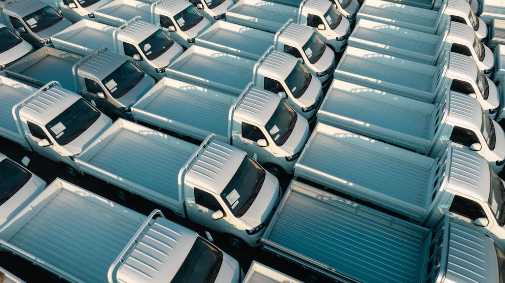 Aerial view of white pickup trucks parked in rows, emphasizing symmetry and industrial style.