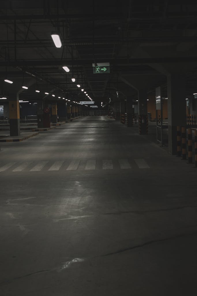 A dark underground parking lot featuring empty spaces and overhead lighting.