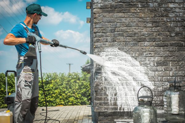 man doing pressure washing outside the building